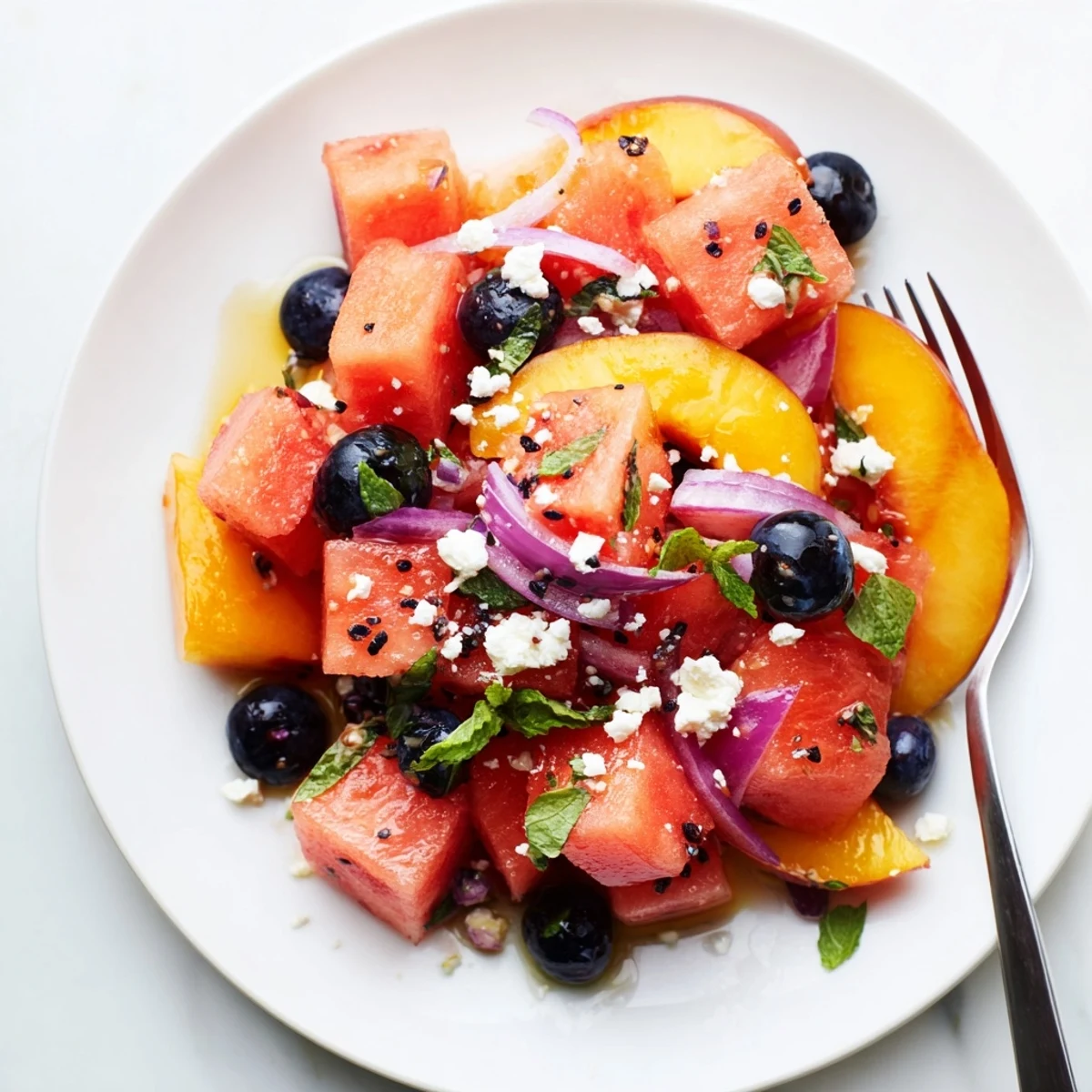 Picnic-ready Peach Watermelon Salad With Feta finished with herbs and toasted pine nuts