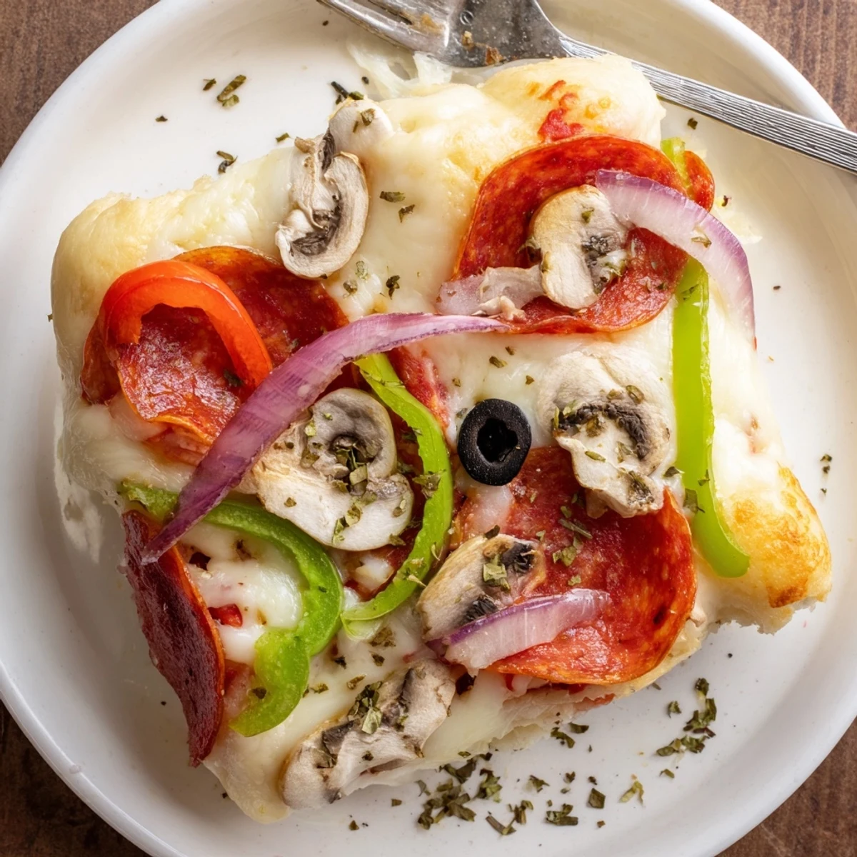 Slice of Focaccia Pizza Supreme resting on wooden board, olive oil sheen
