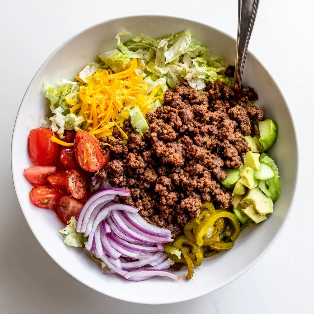 Meal-prep Savory Protein Packed Burger Bowls layered with tangy sauce, avocado, and tomatoes.