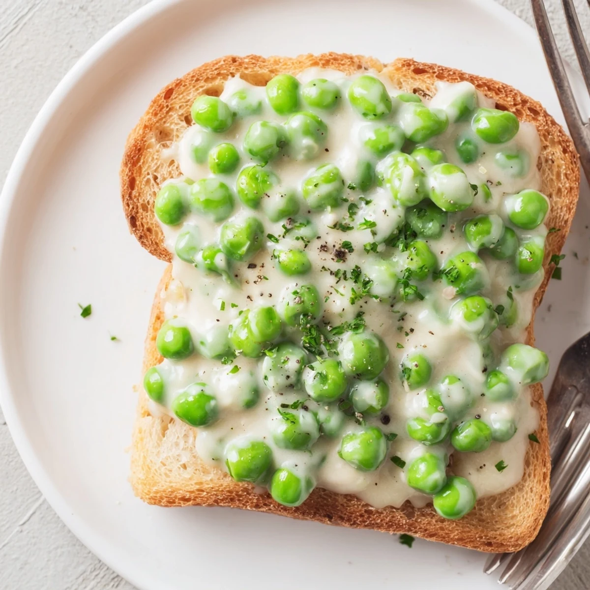 Warm Creamed Peas on Toast garnished with chopped parsley and cracked pepper