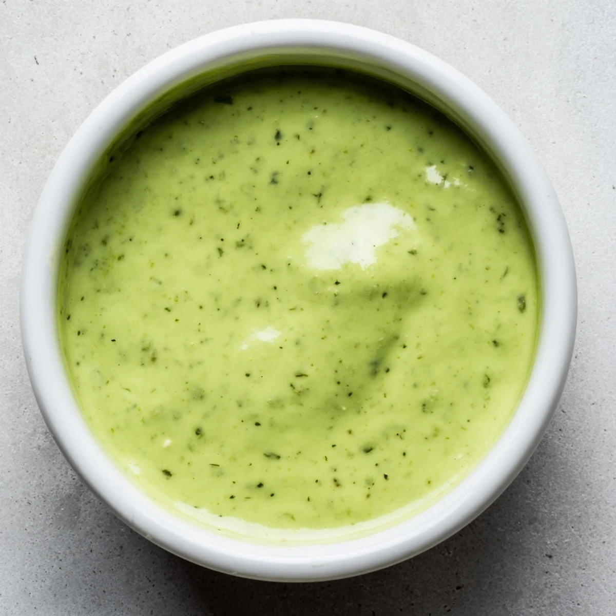Vibrant green cilantro lime sauce in a glass bowl ready for dipping crispy tortilla chips