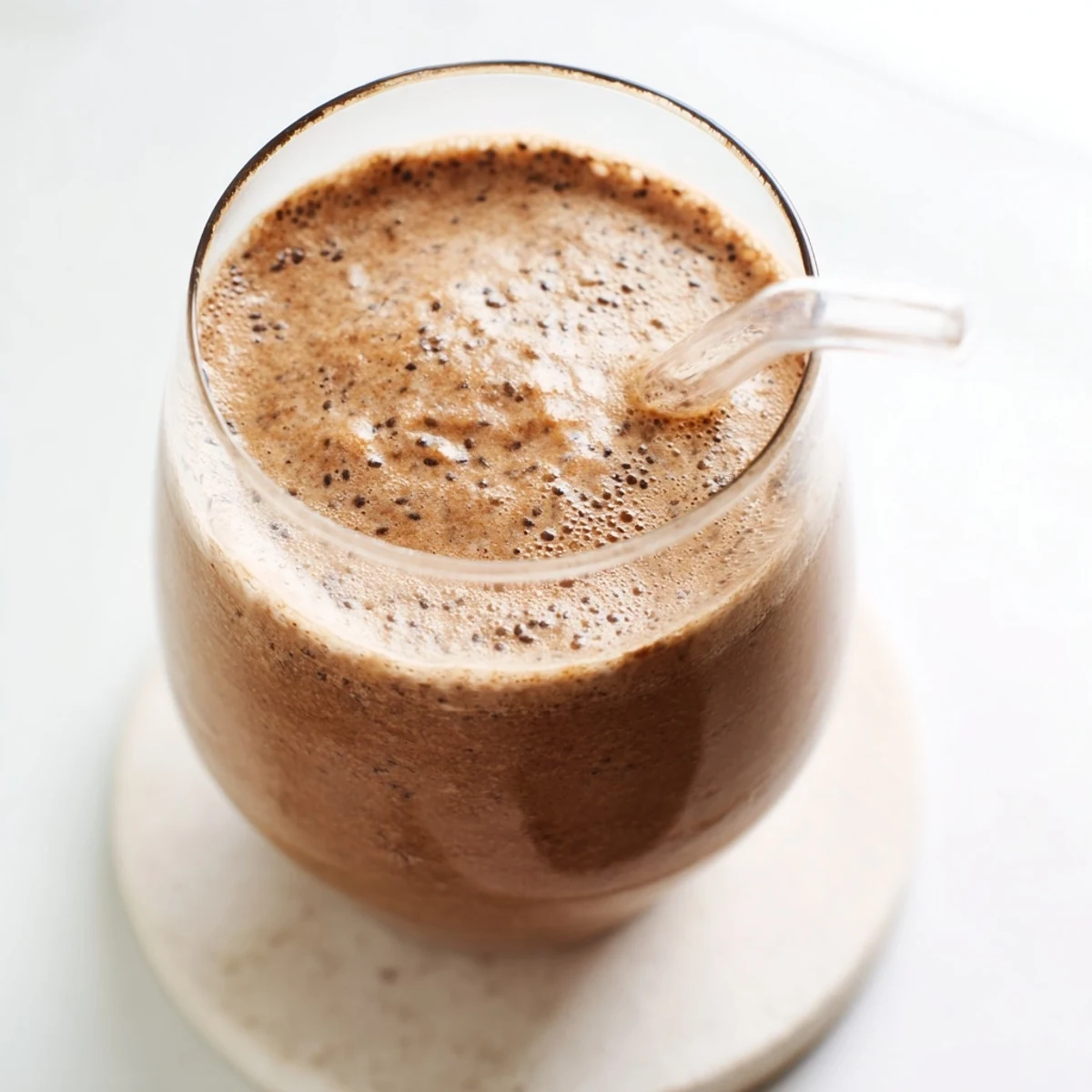 Creamy raw chocolate banana shake poured into tall glasses with frothy chocolate bubbles on top