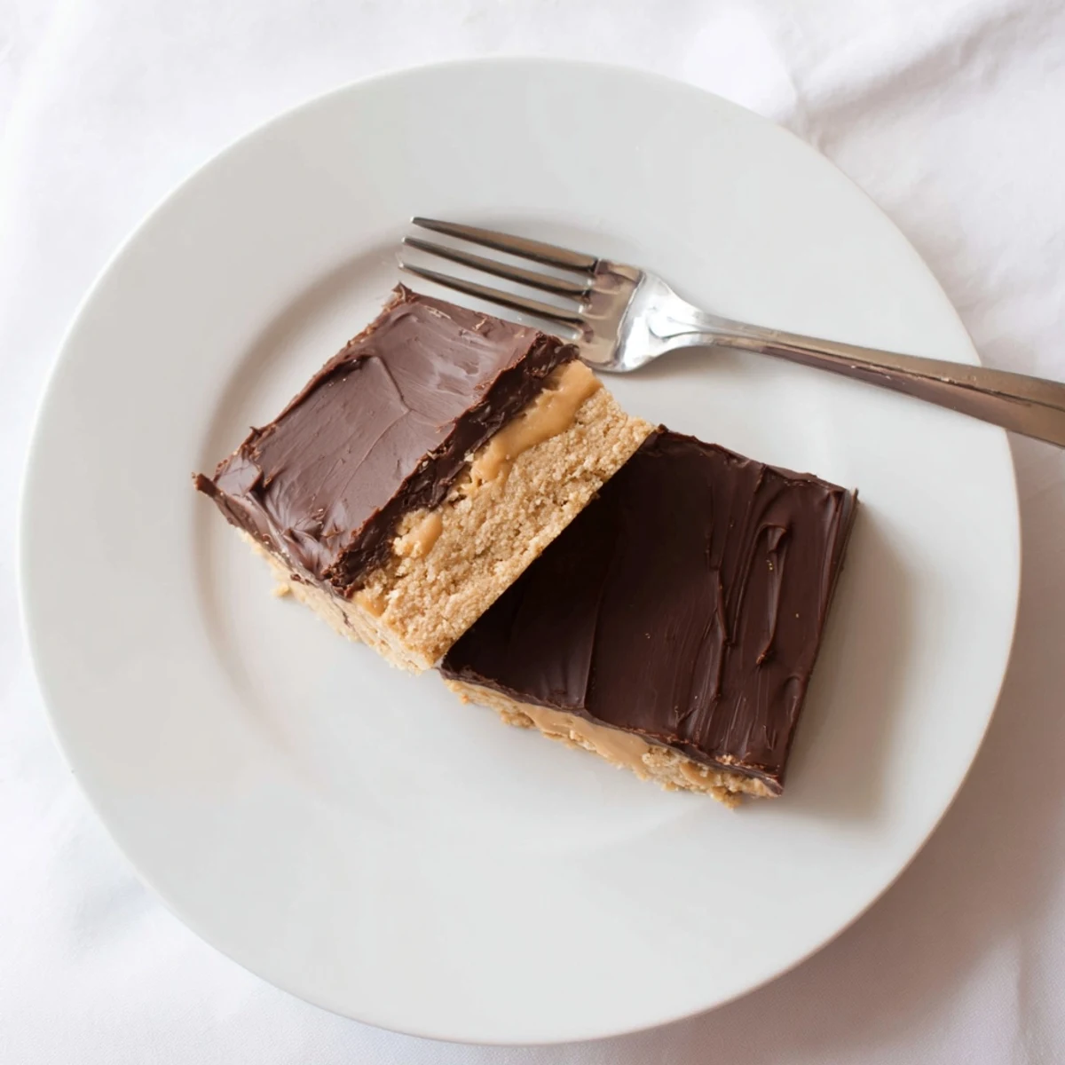 Golden peanut butter bars sliced into squares with glossy chocolate layer on top