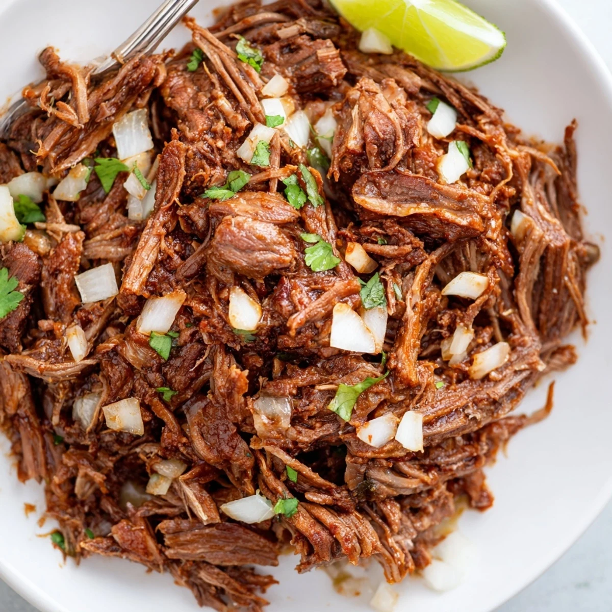 Slow Cooker Beef Barbacoa piled on warm tortillas with cilantro and lime