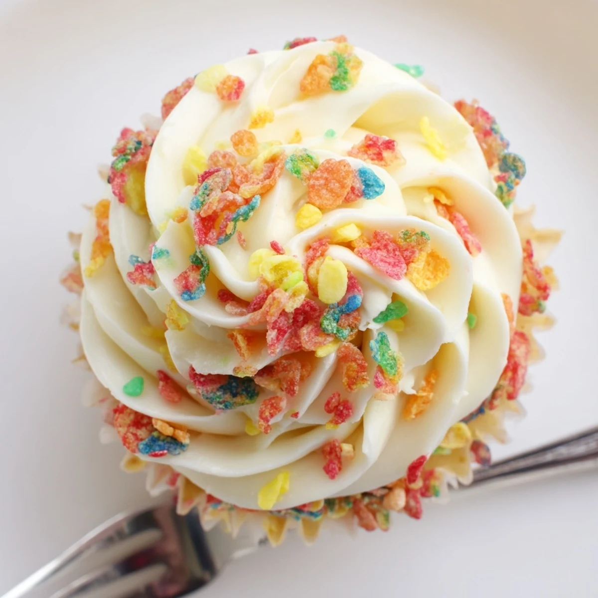 Fruity Pebbles Cereal Frosting swirled on vanilla cupcakes, glossy, crunchy garnish.