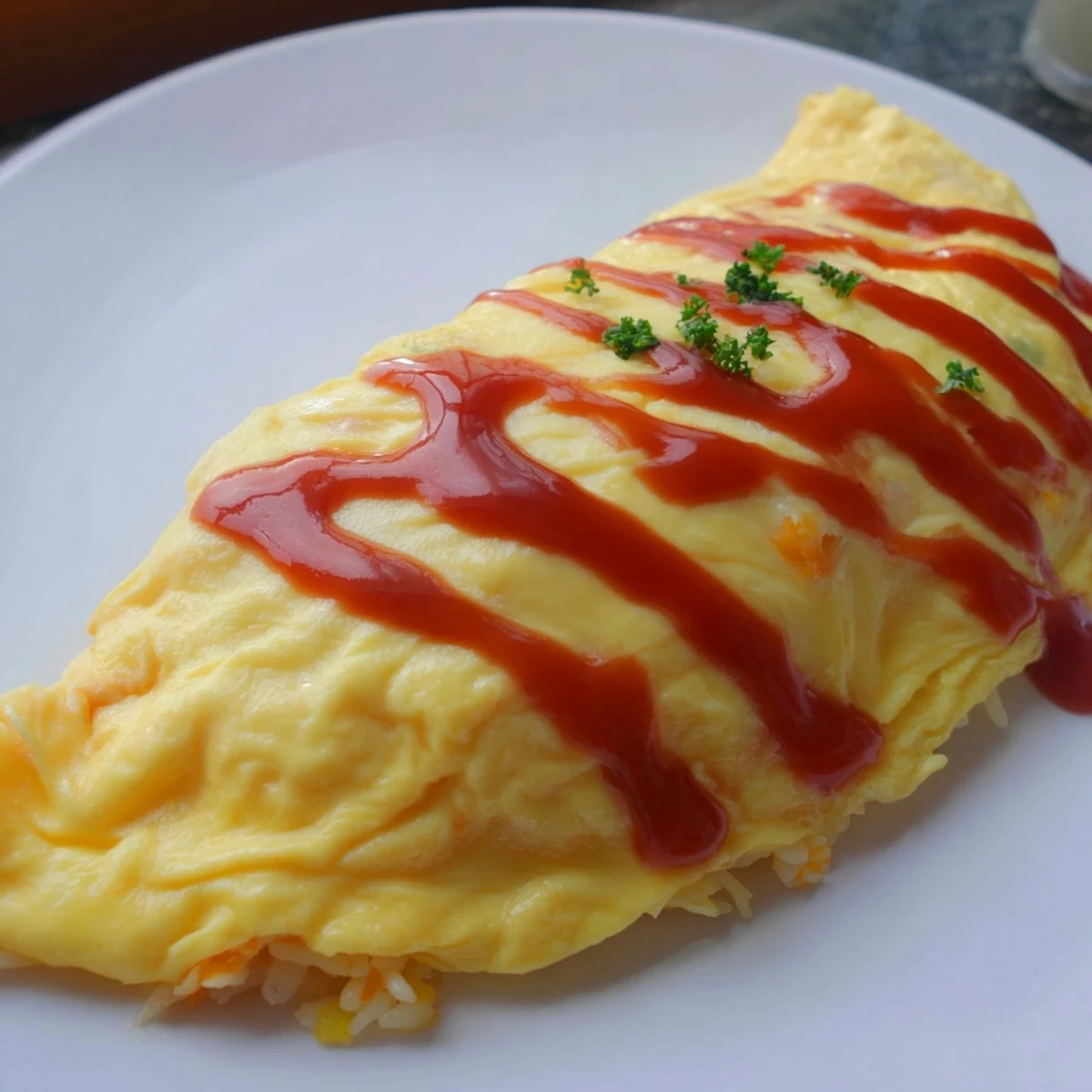 Golden omurice with a silky omelette draped over ketchup fried rice, drizzled with sauce