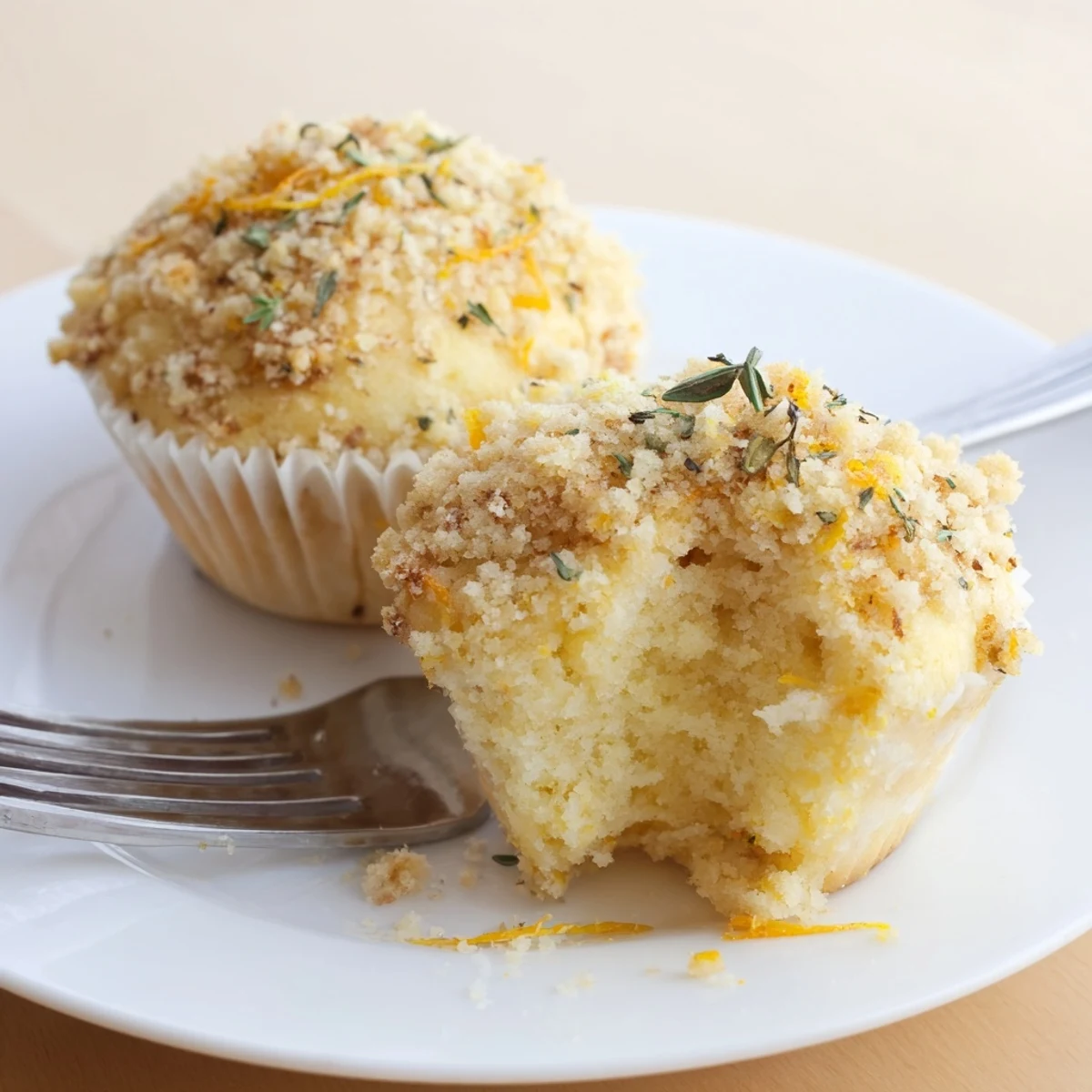 Moist citrus muffins topped with a fragrant golden thyme crumble on a rustic plate