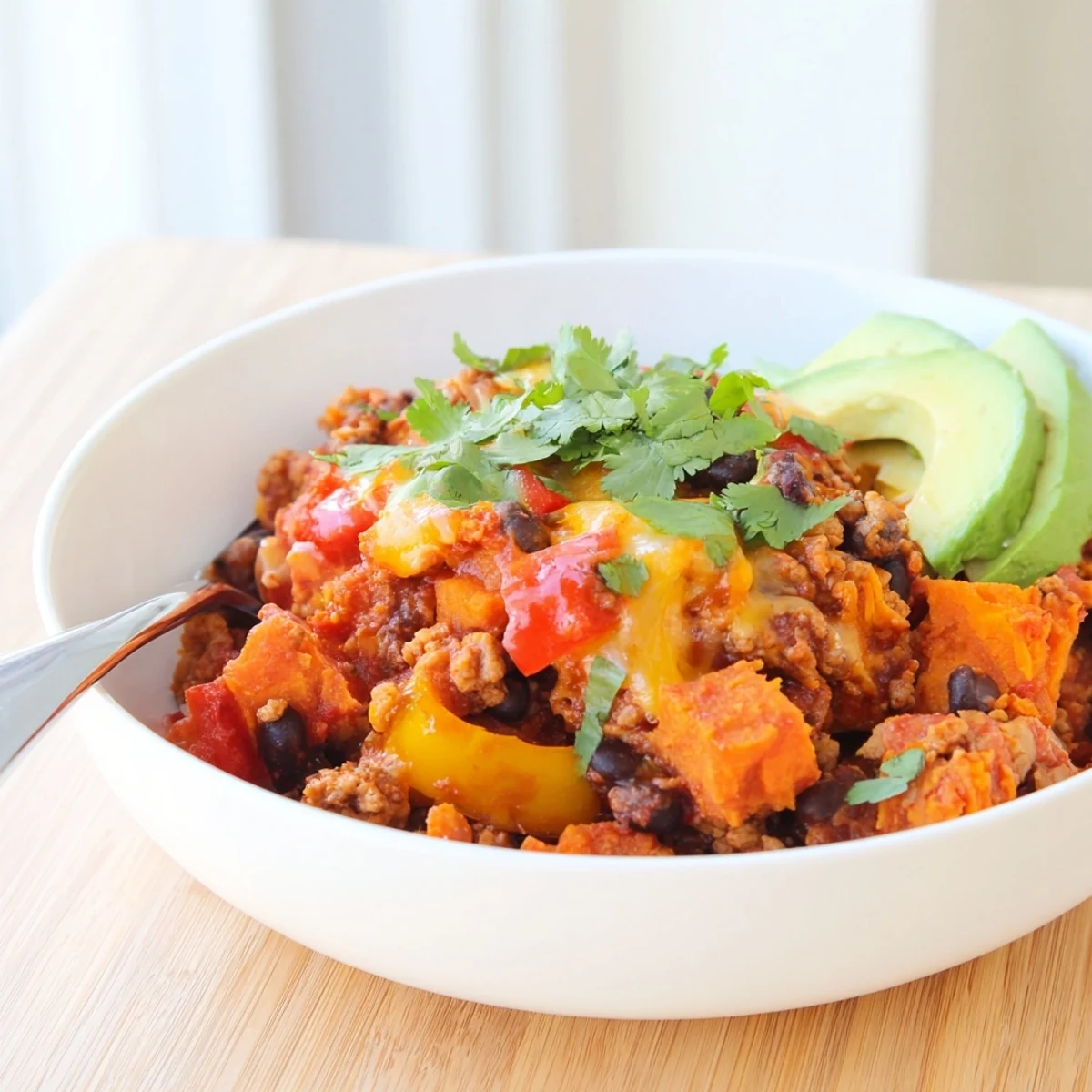 Sweet potato turkey black bean bake bubbling in a rustic casserole dish with avocado slices