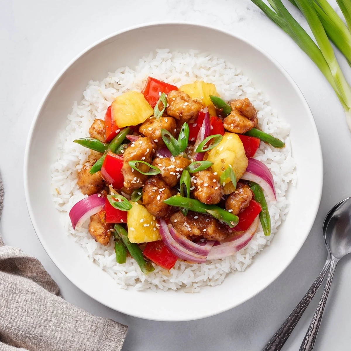 Vibrant pineapple chicken rice bowl topped with crisp snap peas, glossy sauce, and sesame seed garnish