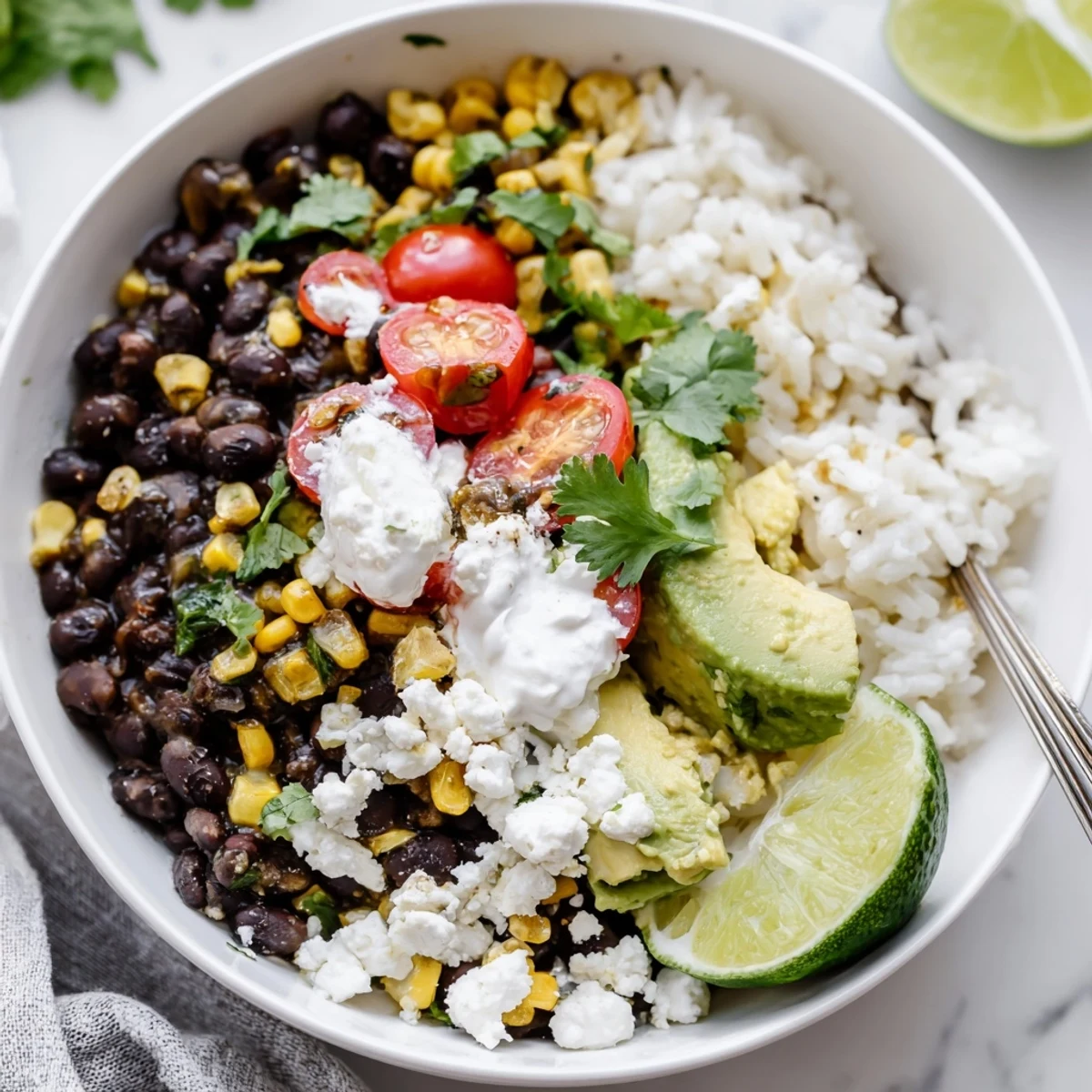 Steaming black bean and rice bowl garnished with creamy avocado and lime wedges