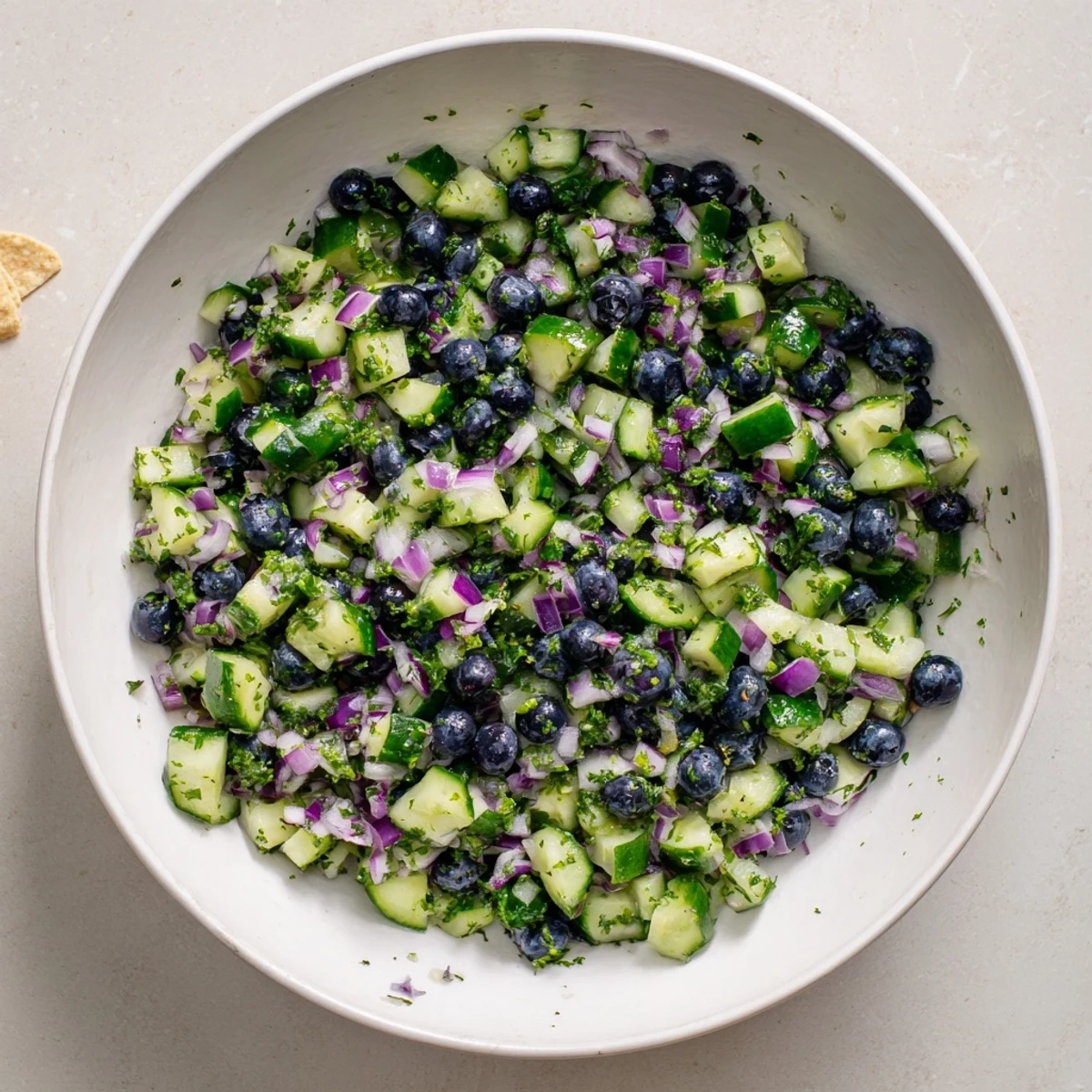Colorful blueberry cucumber salsa topped with cilantro and lime zest in a rustic dish