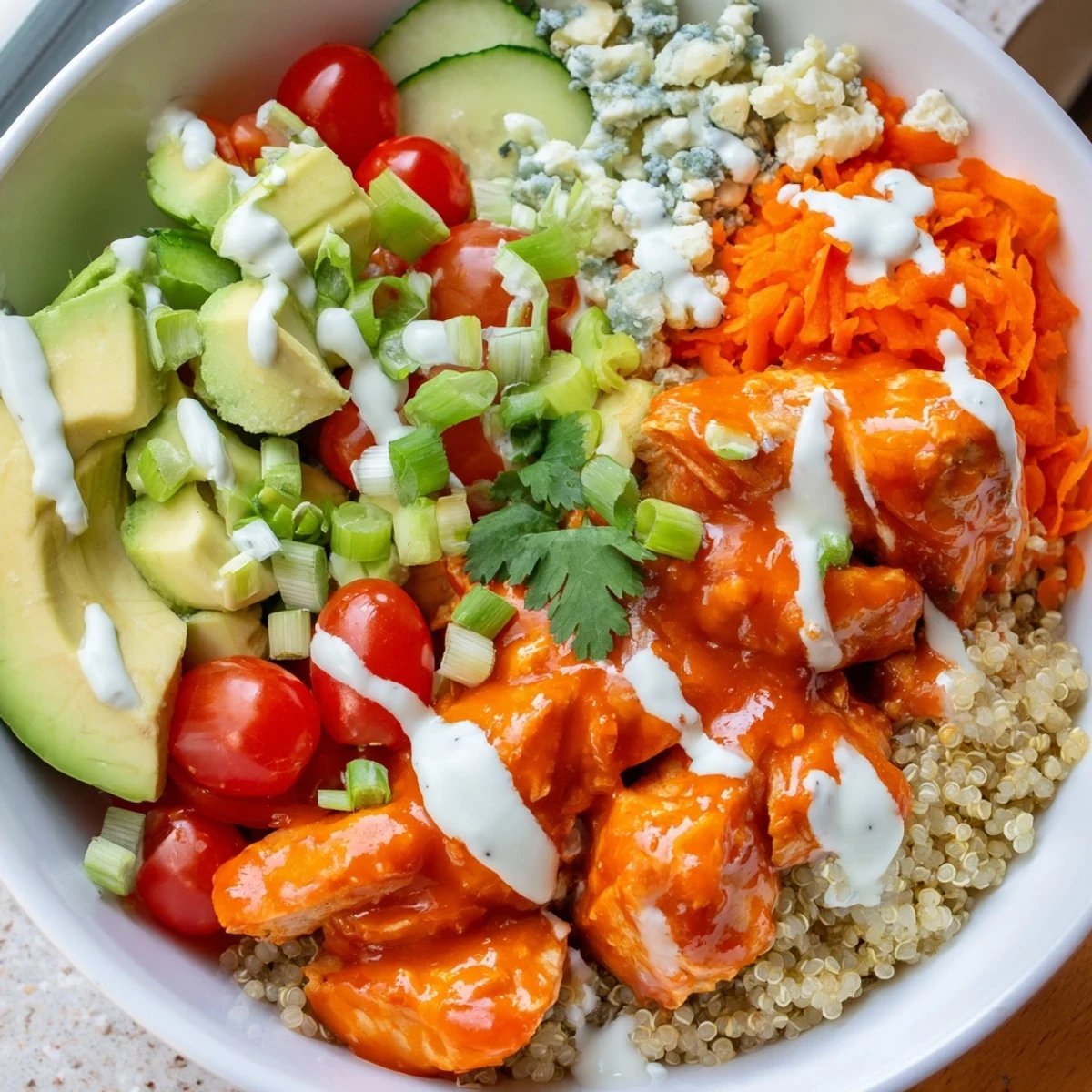 Golden buffalo chicken grain bowl served over fluffy quinoa with fresh avocado slices