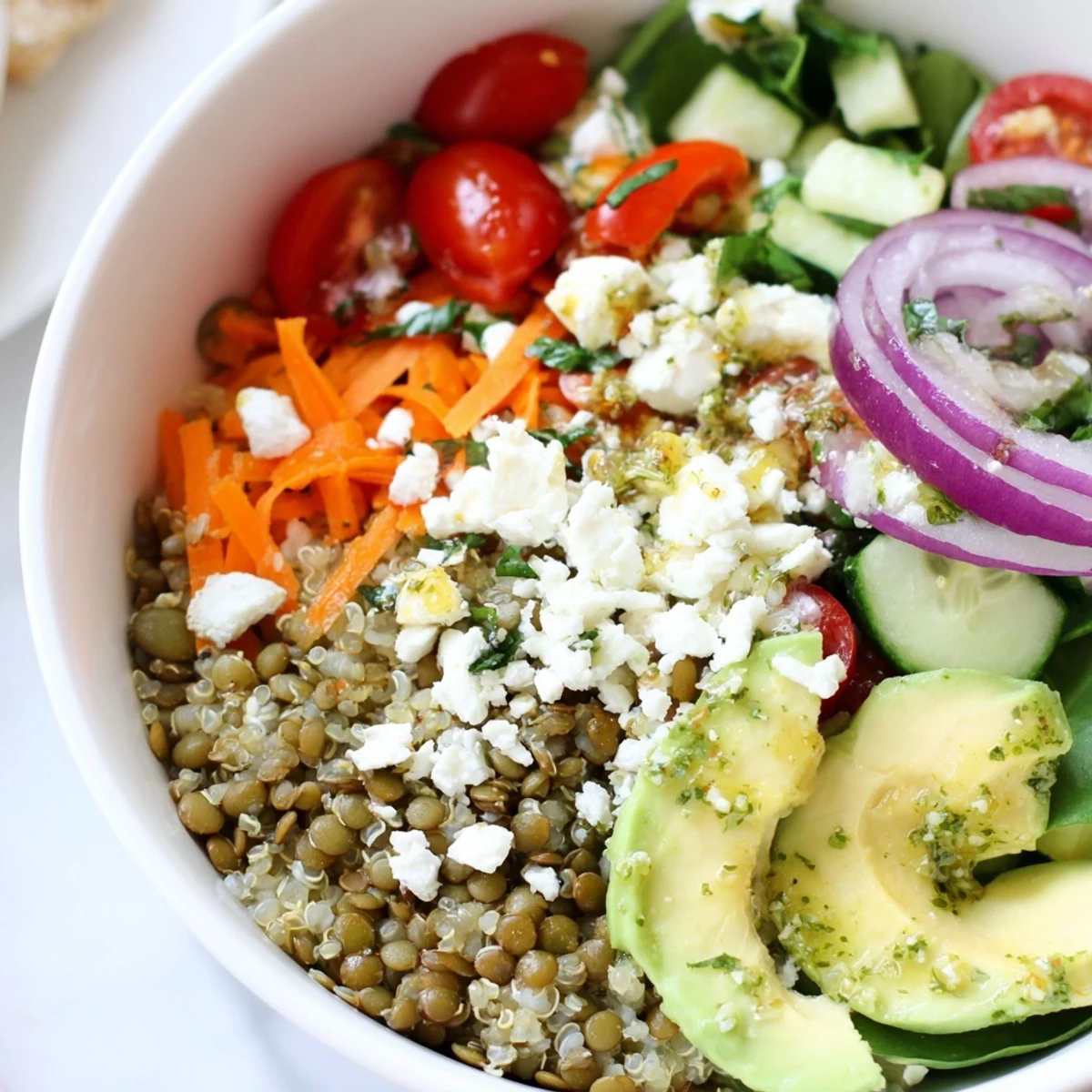Colorful lentil grain bowl topped with fresh cherry tomatoes, avocado, and herbed dressing