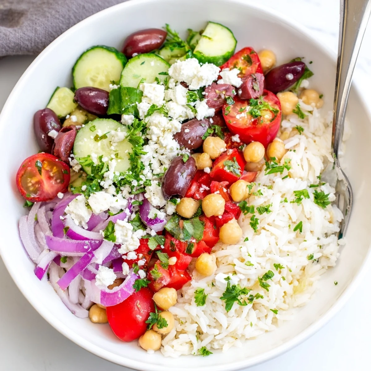 Colorful Mediterranean rice bowl topped with cherry tomatoes, cucumber, chickpeas, and crumbled feta cheese
