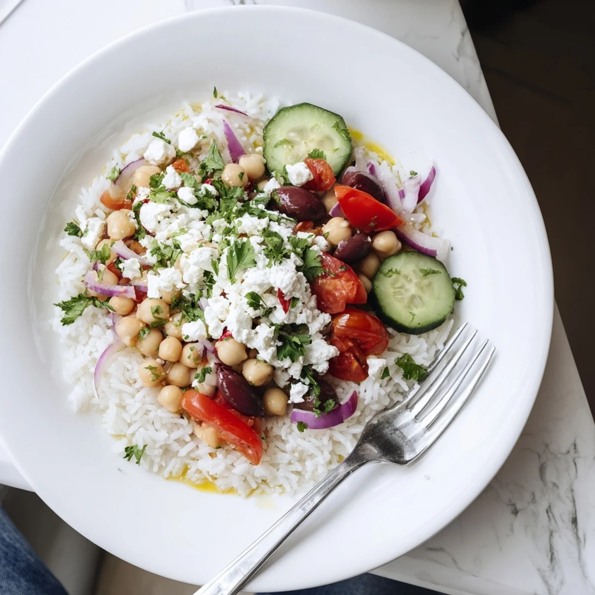 Fresh Mediterranean rice bowl drizzled with lemon herb dressing and brimming with vibrant chopped vegetables