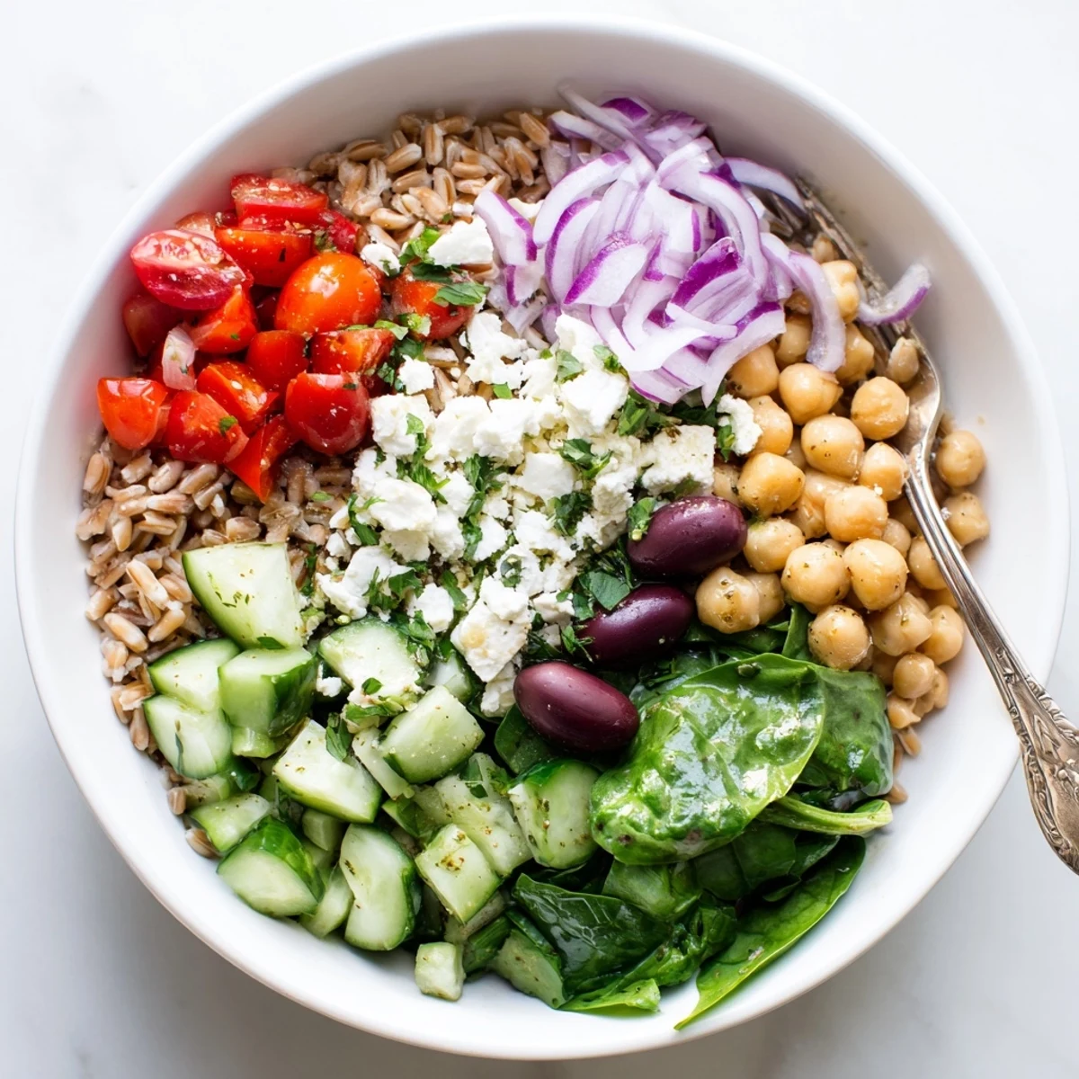 Colorful Mediterranean grain bowl topped with crisp veggies, crumbled feta, and zesty lemon dressing