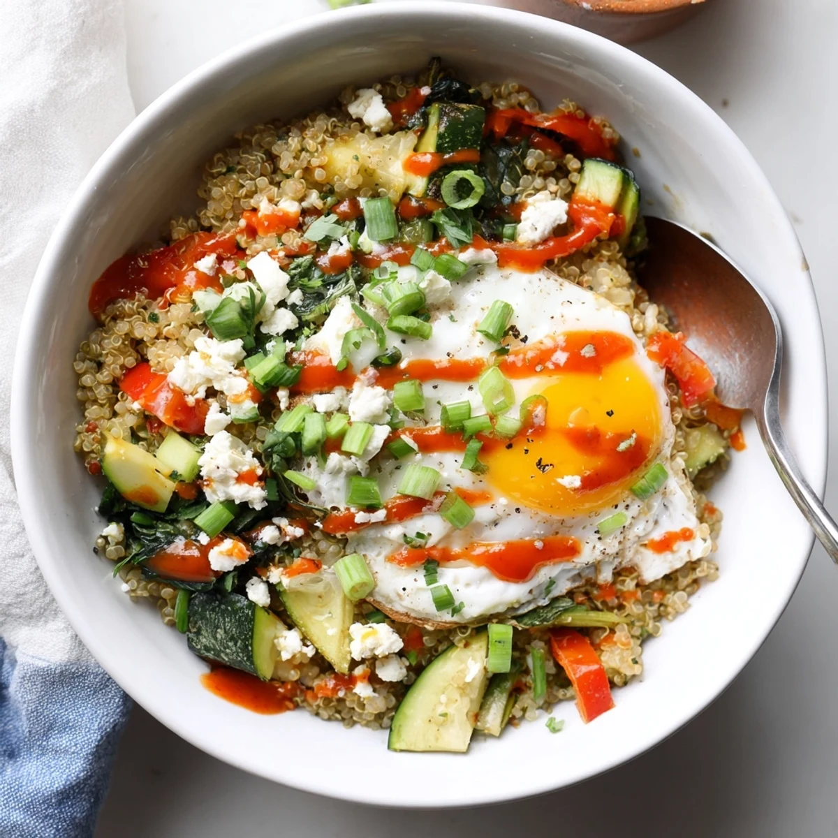 Warm savory quinoa breakfast bowl topped with a runny egg and sautéed vegetables