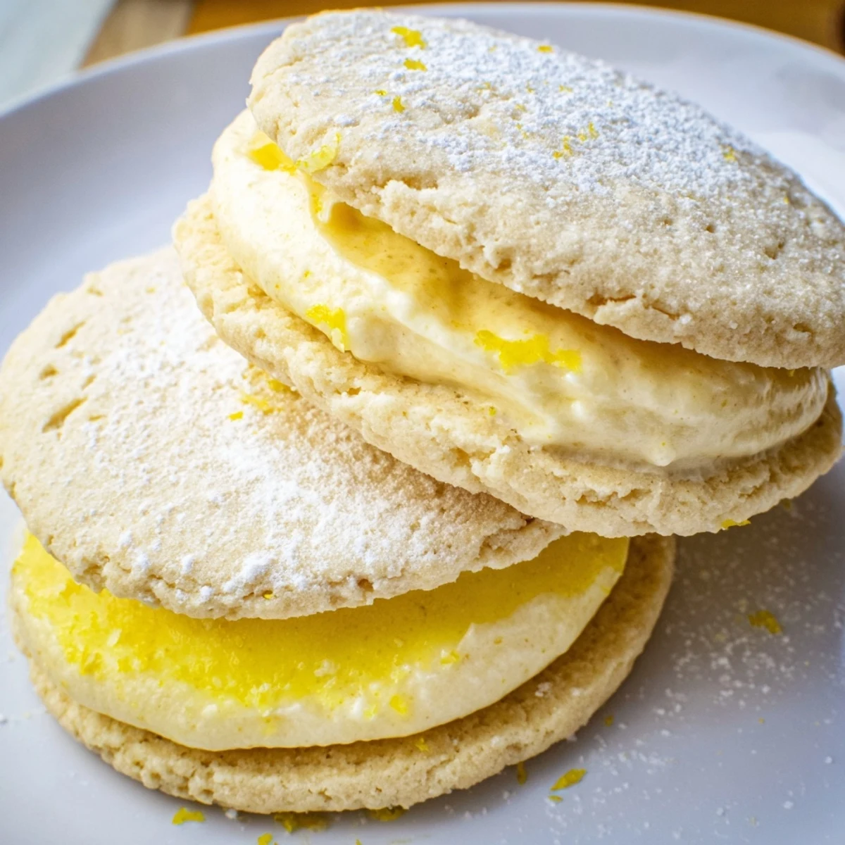Bright vegan lemon sandwich cookies dusted with powdered sugar ready for serving