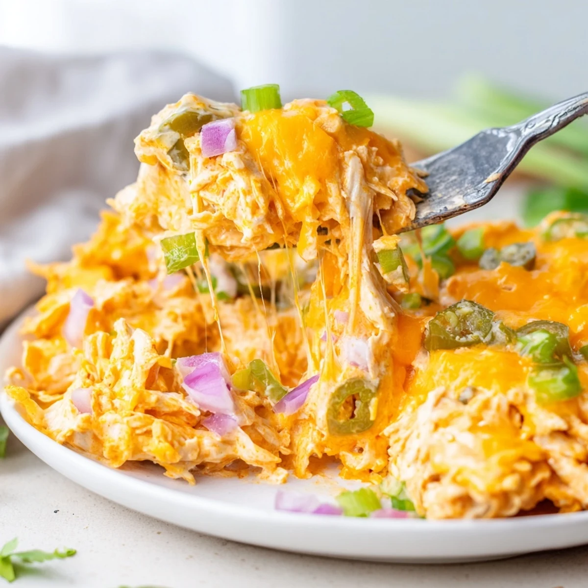 Creamy jalapeno buffalo chicken casserole served in a rustic dish with fresh green onion garnish