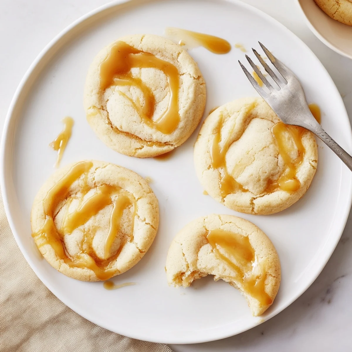 Creamy caramel cheesecake cookies swirled with rich sauce on parchment paper