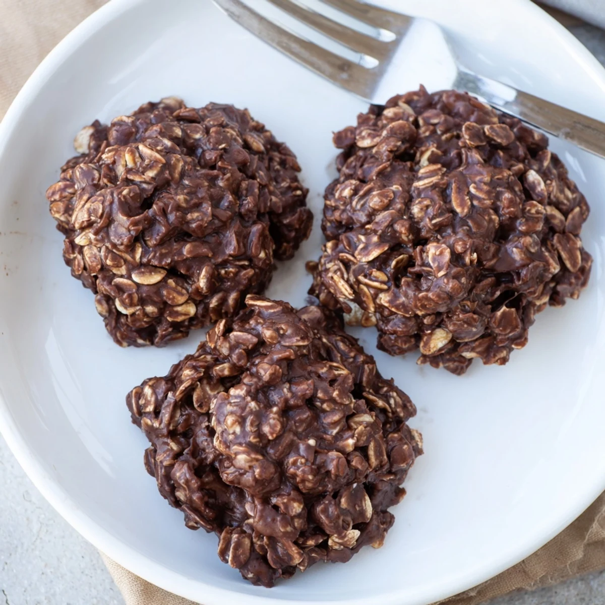 Glossy chocolate oatmeal no bake cookies cooling into soft chewy rounds on wax paper