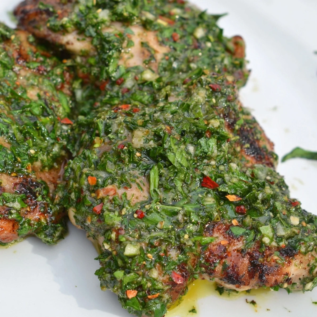Perfectly cooked chimichurri chicken thighs on a plate, garnished with parsley.