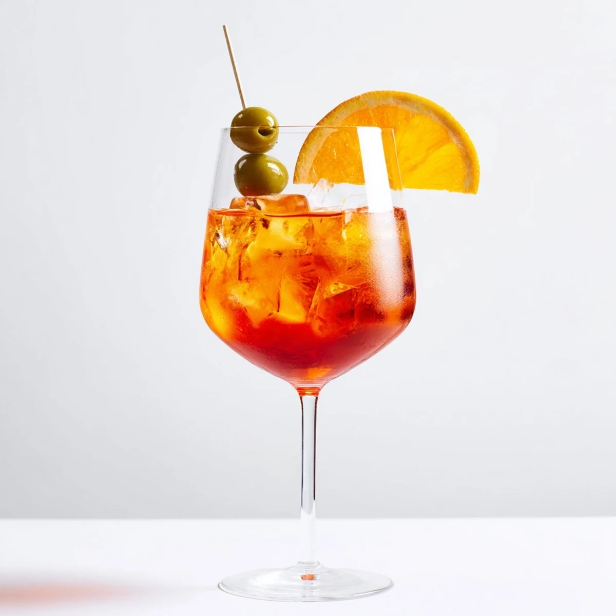 Bright orange Spritz cocktail garnished with fresh orange slice on ice.  