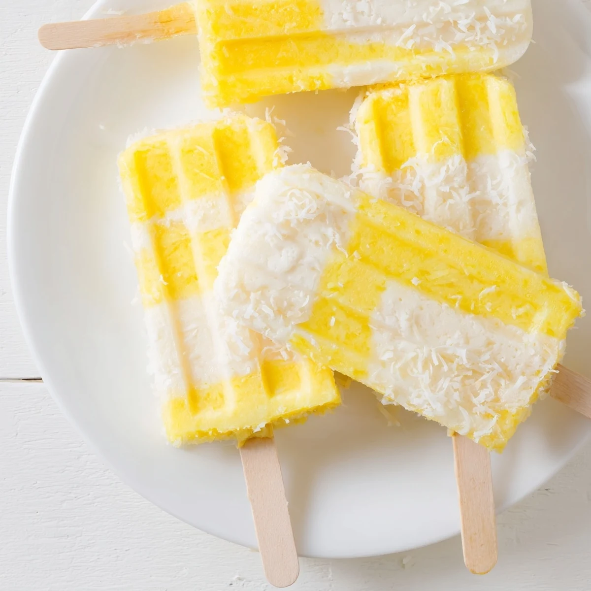 Creamy pineapple coconut lime popsicles in molds with a vibrant marbled swirl