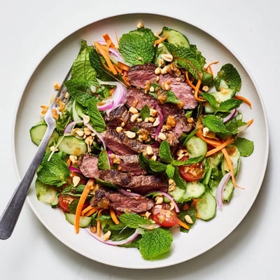 Tender marinated steak meets crunchy cucumbers and peppery greens in this vibrant Vietnamese Beef and Watercress Salad, topped with chopped peanuts and fresh herbs.