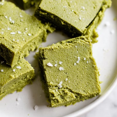 The finished 5-Ingredient Matcha Halva is cut into cubes on a marble countertop, showing the crumbly texture and vivid matcha color.