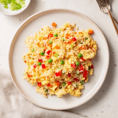 A serving of spicy Bang Bang Fried Rice garnished with green onions and a lime wedge.
